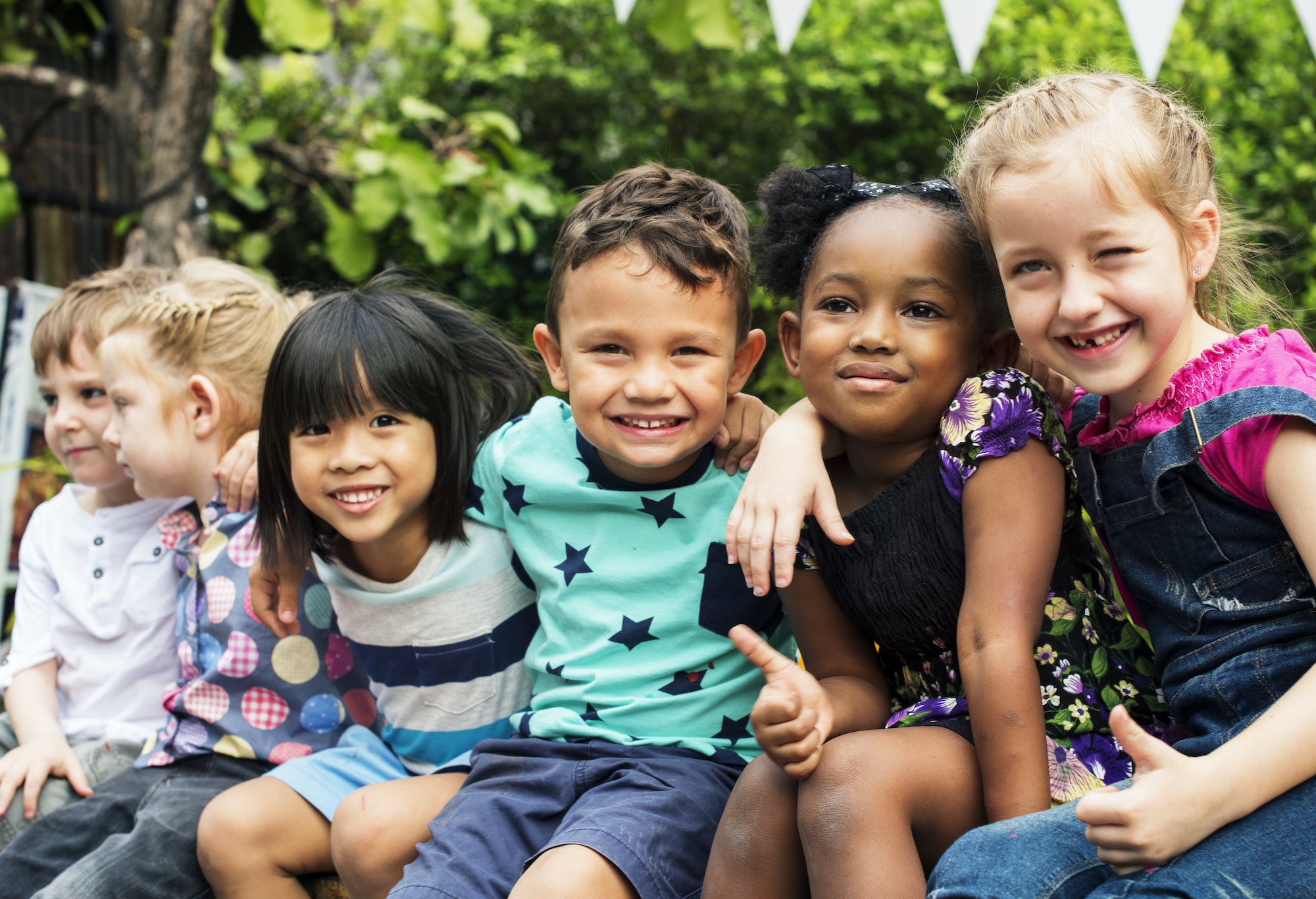 Group of kindergarten kids friends arm around sitting and smiling fun